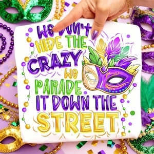 Puede incluir: Cuadrado blanco con el texto "We Won't Hide The Crazy We Parade It Down The Street" en morado, verde y dorado. Una máscara morada y dorada con plumas está a la derecha. Tema de Mardi Gras.