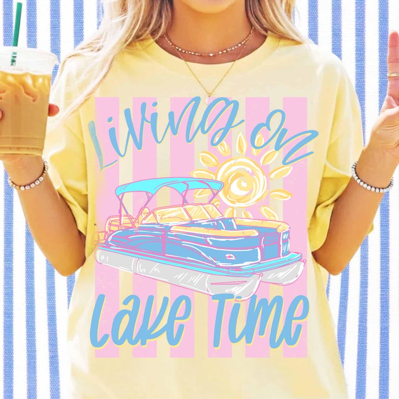 May include: Yellow t-shirt with the text "Living on Lake Time" in blue script. The design features a blue and pink pontoon boat with a sun graphic. The shirt has a relaxed fit.