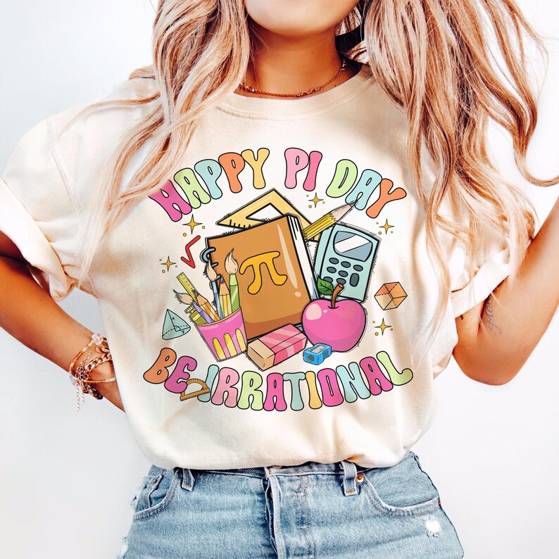 May include: A white t-shirt with the text "Happy Pi Day Be Irrational" in rainbow colors. The design includes a book with the symbol for pi, a calculator, pencils, a ruler, an apple, and a pencil holder.