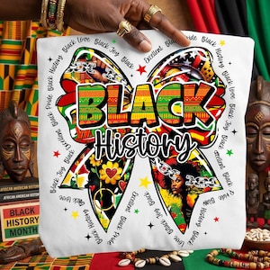 May include: White tote bag featuring a colorful bow design with the words "BLACK History" in bold letters. The bow is decorated with various patterns, including a portrait of a woman, flowers, and chains. The words "Black Joy," "Black Love," and "Black Pride" are also included.