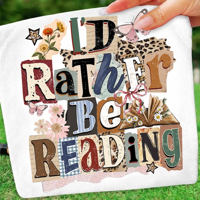 May include: White decorative pillow with the text "I'd Rather Be Reading" in a collage style. The design includes floral and butterfly accents, and a star-shaped embellishment. The pillow is held by a hand.