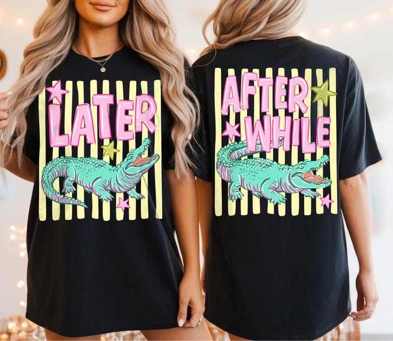 May include: Black t-shirt featuring a teal alligator graphic with the words "LATER" and "AFTER WHILE" in pink. The design includes yellow stripes and star accents, creating a playful and eye-catching design. A casual, unisex tee.