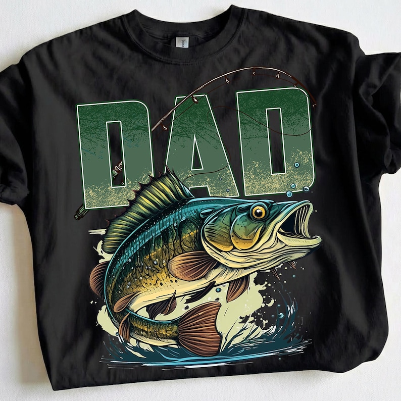 Pu&ograve; includere: T-shirt nera con una grafica di un pesce che salta fuori dall'acqua e la parola "DAD" in verde sopra. Il pesce &egrave; dettagliato con squame blu, verdi e marroni, e una canna da pesca &egrave; arcuata sopra.