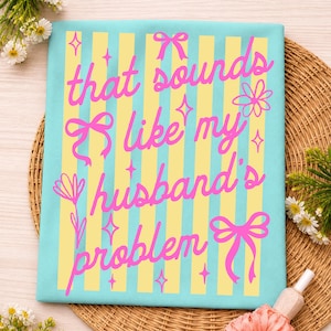 May include: A light blue decorative square with yellow vertical stripes and the text "that sounds like my husband's problem" in pink script. The design includes pink bows, flowers, and starbursts.