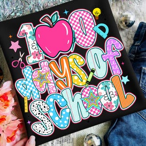 May include: Black t-shirt with a colorful graphic that reads "100 Days of School." The design includes a pink apple, stars, scissors, and other school-themed elements in various patterns and colors.