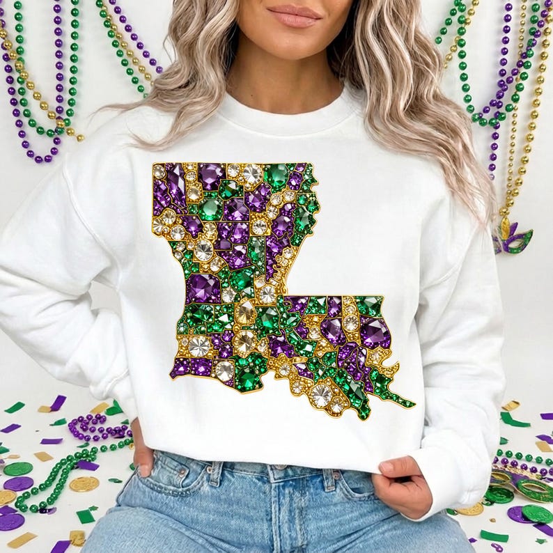 May include: White sweatshirt featuring a jeweled Louisiana state outline in green, purple, and gold. The design is made of sparkling gems. The sweatshirt is a crew neck style.
