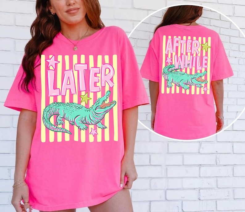 May include: A bright pink t-shirt with a graphic of a teal alligator and the word "LATER" in pink. The back of the shirt has the words "AFTER WHILE" and another alligator graphic. Yellow stripes and star accents complete the design.