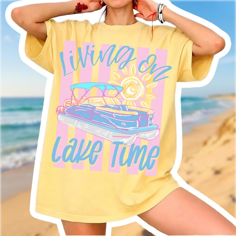 May include: Yellow t-shirt with a graphic of a pontoon boat, sun, and text "Living on Lake Time" in blue and pink. The shirt has a relaxed fit and short sleeves.