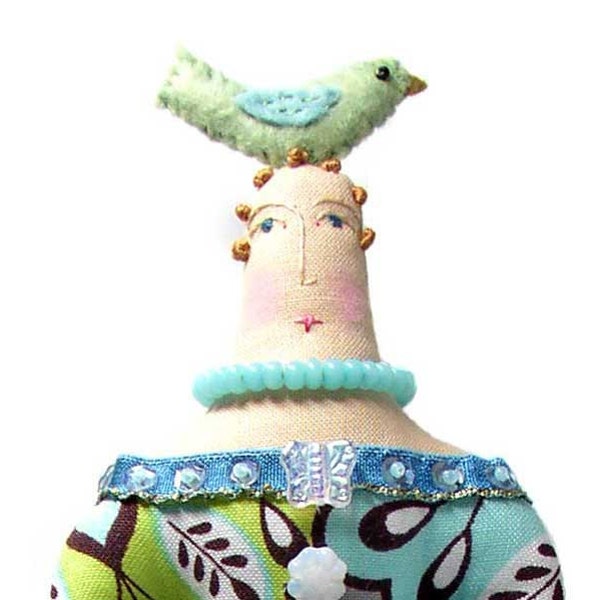 Textile art cloth doll with a blue winged green bird on top of her head