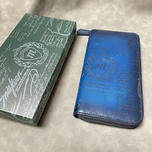 Esta es una billetera larga hecha a mano, teñida y redonda con cremallera y elementos de caligrafía. Es una billetera de ensueño para hombre de color verde cobre hecha en Italia.