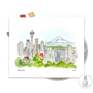 May include: Watercolor painting of the Seattle skyline with the Space Needle and Mount Rainier in the background. The painting is on a white background with the text "Seattle, WA" in the bottom left corner.