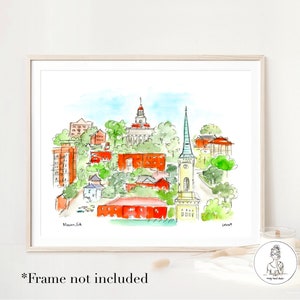 Op de afbeelding: Waterverfillustratie van de skyline van Macon, Georgia, met een hoge kerktoren, een rood bakstenen gebouw met een koepel en andere gebouwen en bomen. De tekst "Macon, GA" staat in de linkerbenedenhoek van de afbeelding.