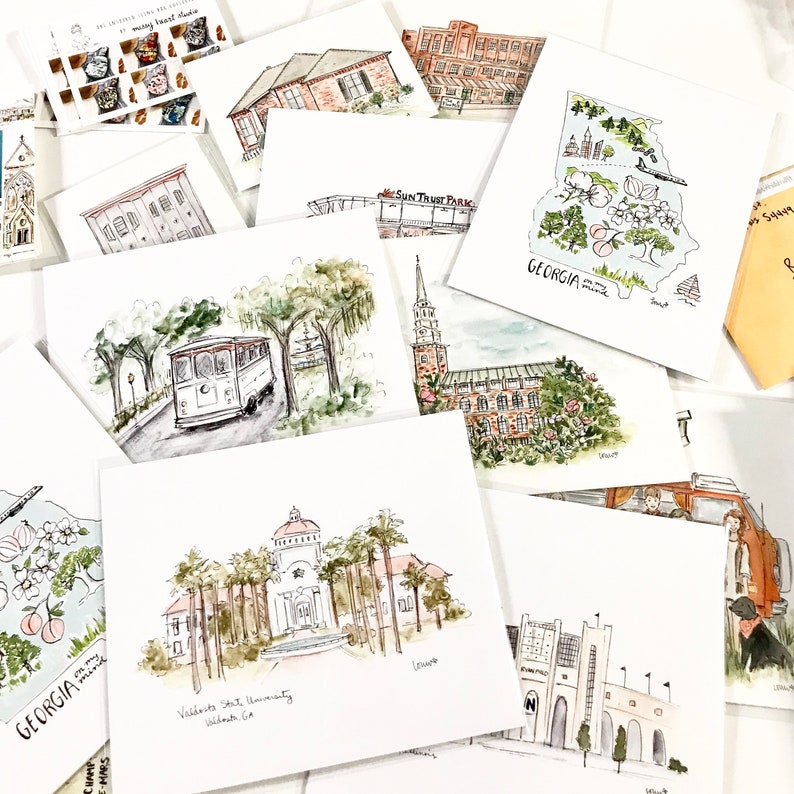 Puede incluir: Una colecci&oacute;n de ilustraciones de acuarela de varios monumentos y lugares de Georgia, incluyendo el contorno del estado, el SunTrust Park, la Universidad Estatal de Valdosta y un tranv&iacute;a.