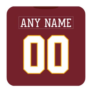 May include: A maroon sports jersey featuring the text ANY NAME in white block letters inside a thin white rectangular border, positioned above the large white numbers 00, which are outlined in a thin yellow border against the solid maroon fabric.