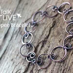 May include: A copper wire bracelet with a loopy design. The bracelet is made of multiple interconnected circles of wire. The bracelet is on a wooden surface.