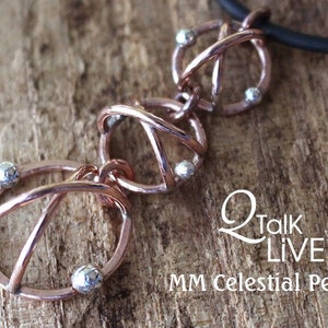 May include: A copper-colored pendant necklace with three circular, interwoven designs, each adorned with small, silver-colored beads. The pendant hangs on a black cord. The text "Q Talk LIVE" and "MM Celestial Pendant" are visible.