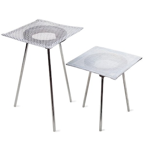 May include: Two metal tripod stands with square, mesh tops. The stands have three legs each and are made of shiny, silver-colored metal. The mesh tops are also silver and have a fine, grid-like pattern. The stands are likely used in a laboratory setting.