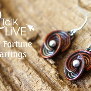 May include: A pair of copper and silver fortune earrings with a spiral design. The earrings are hanging from silver hooks.