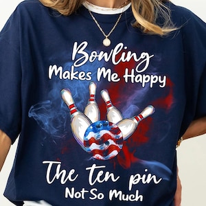 May include: A navy blue t-shirt with a bowling ball and pins graphic. The text on the shirt reads "Bowling Makes Me Happy The Ten Pin Not So Much".