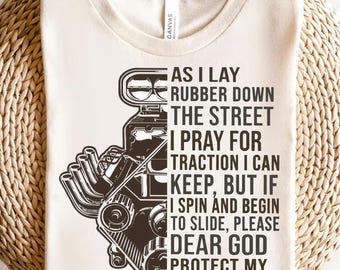 May include: A white t-shirt featuring a black and white illustration of a car engine. The text on the shirt reads: "As I lay rubber down the street I pray for traction I can keep, but if I spin and begin to slide, please dear God protect my sweet ride."
