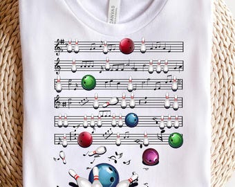 May include: White t-shirt with a musical staff design featuring bowling pins and bowling balls. The bowling pins and balls are in various colors, including red, green, blue, and purple. The musical staff has notes and clefs.