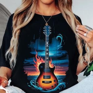 A woman wearing a black t-shirt with a graphic design of a guitar and a sunset in the background.