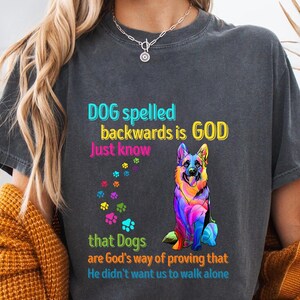 Puede incluir: Camiseta negra con un gráfico de pastor alemán colorido y el texto "DOG spelled backwards is GOD Just know that Dogs are God's way of proving that He didn't want us to walk alone."