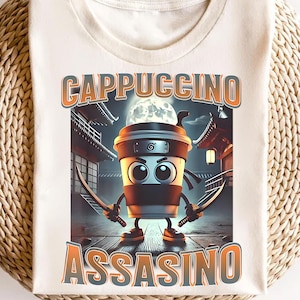 May include: A white t-shirt featuring a cartoon image of a coffee cup dressed as a ninja. The coffee cup has a black mask and is holding two swords. The text "Cappuccino Assasino" is printed on the shirt.
