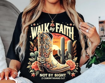 May include: Black t-shirt with a graphic featuring a cowboy boot, cacti, and roses against a sunset backdrop. Text reads "WALK by FAITH NOT BY SIGHT 2 CORINTHIANS 5:7". The boot is tan with intricate detailing.