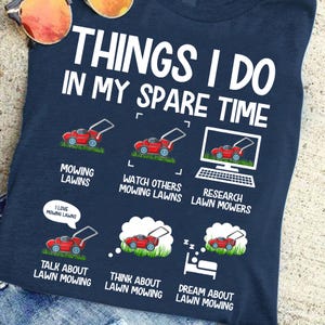 May include: A navy blue t-shirt with white text that reads "Things I do in my spare time". The shirt features a humorous illustration of lawn mowers and the text "Mowing Lawns", "Watch Others Mowing Lawns", "Research Lawn Mowers", "Talk About Lawn Mowing", "Think About Lawn Mowing", and "Dream About Lawn Mowing".