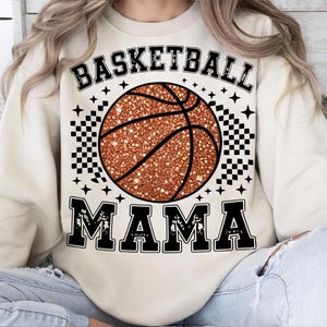 A person wearing a white sweatshirt with a basketball graphic and the text "BASKETBALL MAMA" printed on it.