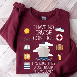 A burgundy sweatshirt with a humorous text and various icons related to travel and cruise control.