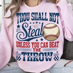 a pink sweatshirt with a graphic design that includes a baseball and text.