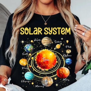 May include: Black t-shirt featuring a colorful solar system design. The shirt displays the text "SOLAR SYSTEM" in yellow, with illustrations of the sun and planets. A great gift for astronomy enthusiasts.