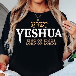May include: Black t-shirt with the word "YESHUA" in white, and the text "KING OF KINGS LORD OF LORDS" in gold. The top features Hebrew text above the word "YESHUA".