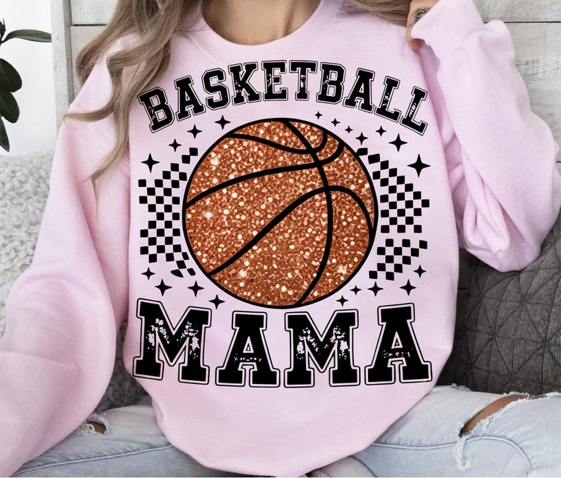 A woman wearing a pink sweatshirt with a basketball graphic and the text "BASKETBALL MAMA" printed on it.