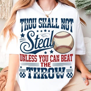 A white t-shirt with a graphic design featuring a baseball and text that reads "THOU SHALL NOT STEAL UNLESS YOU CAN BEAT THE THROW".
