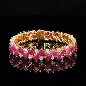 May include: A gold bracelet with a double row of oval-shaped ruby and diamond stones.