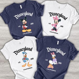 Puede incluir: Cuatro camisetas con dise&ntilde;os de Disneyland. Cada camiseta presenta un personaje diferente de Disney: Mickey Mouse, Minnie Mouse, Donald Duck y Daisy Duck. Las camisetas son azul marino y blancas, con el logotipo de Disneyland y "est. 1955 CALIFORNIA".