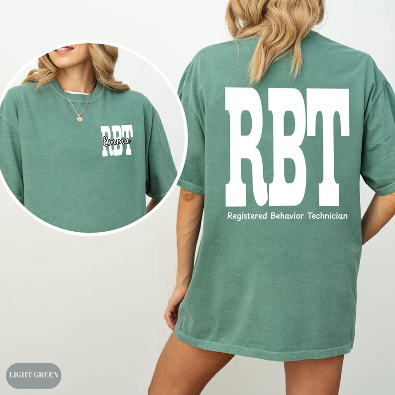 K&ouml;nnte beinhalten: Hellgr&uuml;nes T-Shirt mit den wei&szlig;en Buchstaben "RBT" auf der R&uuml;ckseite und der Vorderseite. Auf der Vorderseite des Shirts steht der Name "Emma" &uuml;ber den Buchstaben "RBT". Der Text "Registered Behavior Technician" steht unter den Buchstaben "RBT" auf der R&uuml;ckseite.