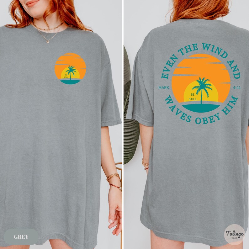 May include: Grey oversized t-shirt with a graphic of a sunset, palm tree, and the words "Mark 4:41 Even the wind and waves obey him" on the back.