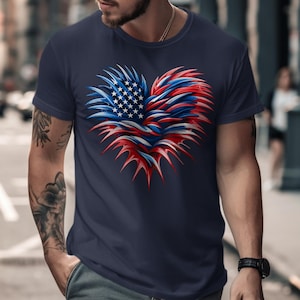 May include: Navy blue t-shirt featuring a heart-shaped design in red, white, and blue, resembling the American flag. The heart has a textured, feathered appearance. The shirt is a classic crew neck style.