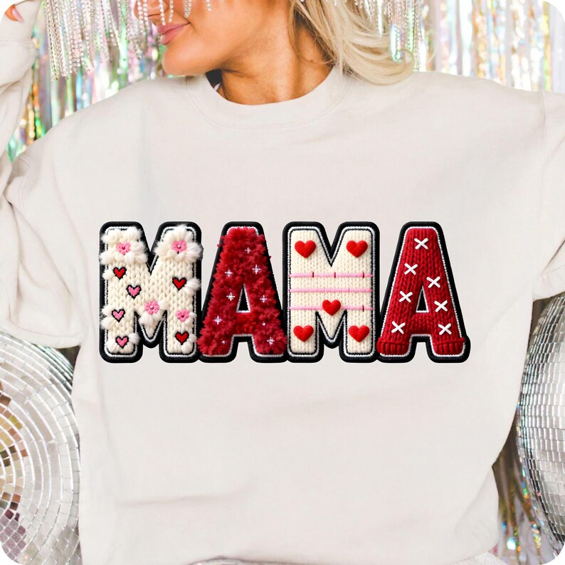 Op de afbeelding: Cr&egrave;mekleurige sweatshirt met het woord "MAMA" in een decoratief, gestikt ontwerp. De letters zijn in rood, wit en roze, met hart- en bloemaccenten. De letters zijn zwart omlijnd.