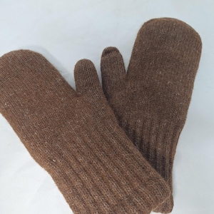 Puede incluir: Un par de mitones de punto marrón. Los mitones están hechos de una tela de punto acanalada y texturizada. El pulgar está separado de los otros dedos. Los mitones están diseñados para mantener las manos calientes en climas fríos.