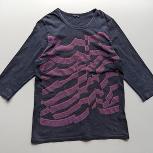 Op de afbeelding: Donkerblauwe longsleeve met een paars ribbenkastontwerp. De shirt heeft een ronde hals en driekwart mouwen. De afbeelding is een gestileerde weergave van een ribbenkast.