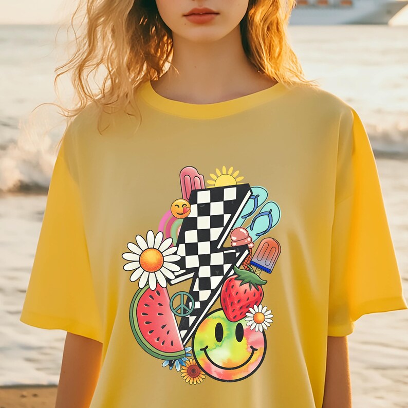 Puede incluir: Camiseta amarilla con un estampado gr&aacute;fico de un rayo a cuadros, una rodaja de sand&iacute;a, una cara sonriente, una margarita, una fresa y un s&iacute;mbolo de paz.
