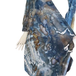 Pode incluir: Um top de envolver azul e marrom com estampa tie-dye, decote em V e mangas curtas.