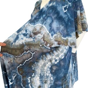 Pode incluir: Um top de envolver azul, marrom e branco com estampa tie-dye, decote em V e mangas curtas.