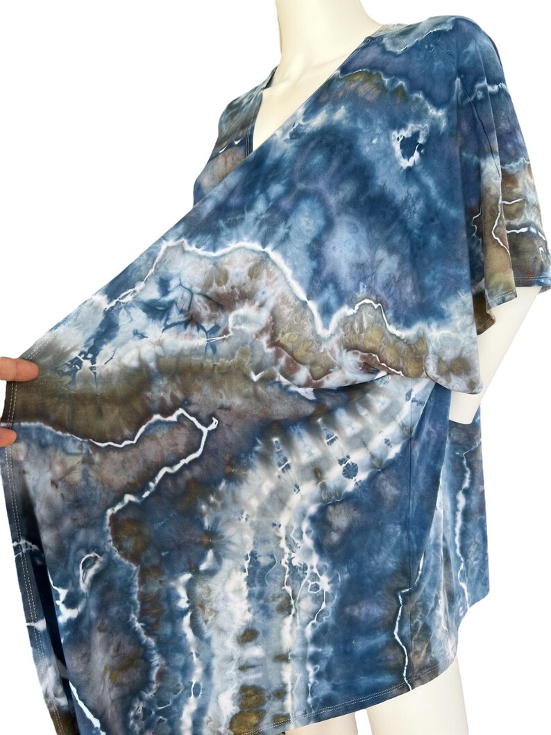 Pode incluir: Um top de envolver azul, marrom e branco com estampa tie-dye, decote em V e mangas curtas.
