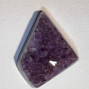 May include: A triangular pendant with a silver setting and a purple amethyst stone.